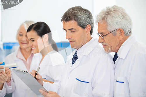 Image of Researchers Discussing Over Clipboard