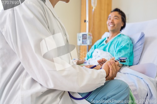 Image of Doctor Sitting With Patient On Hospital Bed