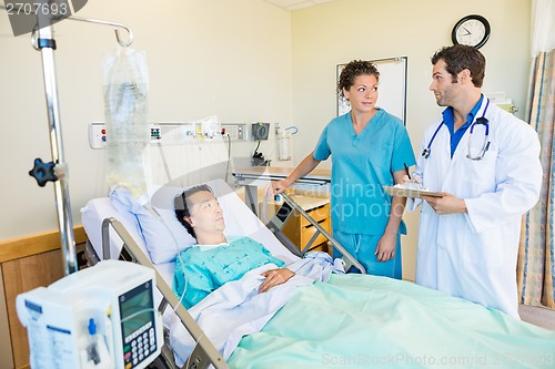 Image of Medical Team Looking At Each Other While Patient On Bed