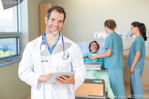 Image of Doctor Using Tablet Computer While Nurses Serving Breakfast To P