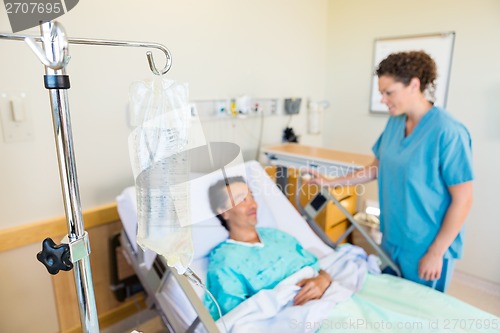 Image of IV Bag With Nurse And Patient Looking At Each Other