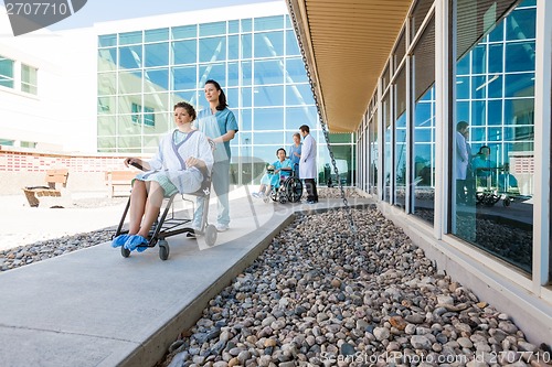 Image of Medical Team With Patients On Wheelchairs At Hospital Courtyard