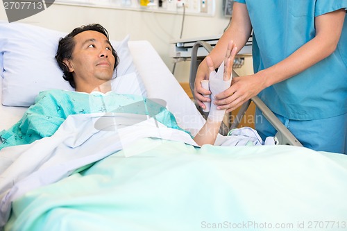Image of Patient Looking At Nurse Putting Bandage On Hand