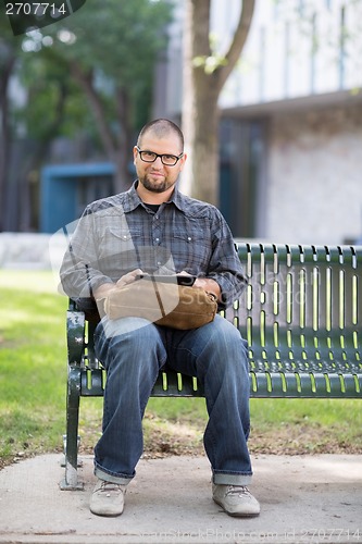 Image of Smiling Male University Student Sitting On Bench