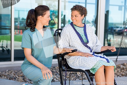 Image of Patient Looking At Nurse While Sitting On Wheelchair