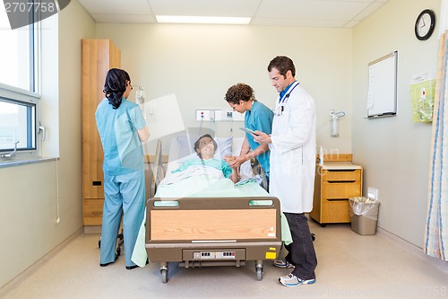 Image of Nurses And Doctor Examining Patient In Hospital