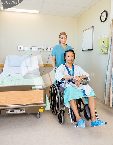 Image of Male Patient Sitting On Wheelchair While Nurse Assisting Him