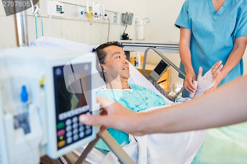 Image of Nurse Putting Bandage On Patient's Hand While Coworker Operating