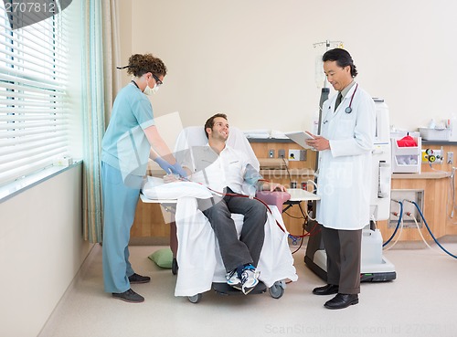 Image of Doctor Using Digital Tablet With Nurse Giving Dialysis To Patien