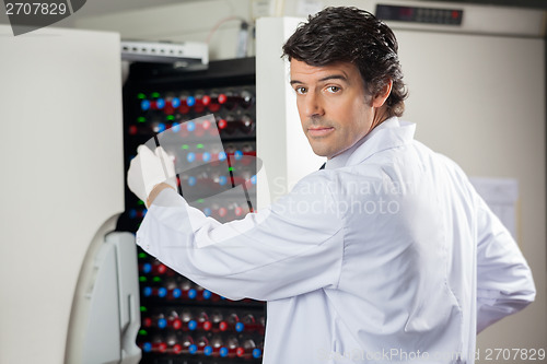 Image of Researcher Placing Bottles Into Blood Culture Instrument