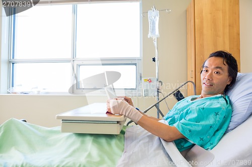 Image of Patient Holding Digital Tablet While Reclining On Bed