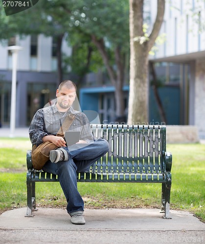 Image of Male Student Using Digital Tablet On Bench At Campus