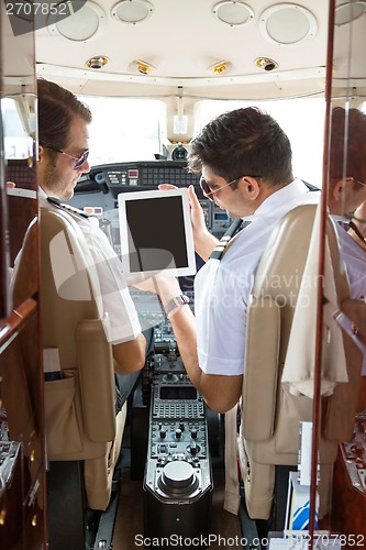 Image of Pilot Showing Digital Tablet To Copilot In Cockpit