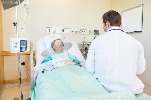 Image of Mature Patient Looking At Doctor While Lying On Hospital Bed