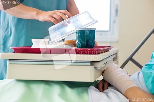 Image of Nurse Lifting Cover From Tray For Patient In Hospital