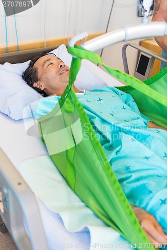 Image of Patient Lying On Sling Of Hydraulic Lift On Hospital Bed