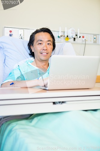 Image of Happy Male Patient Using Laptop On Hospital Bed