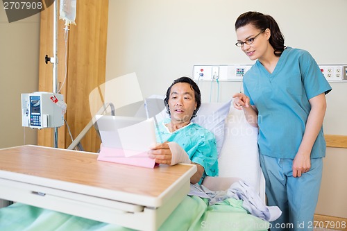 Image of Patient Using Digital Tablet While Nurse Pointing At It