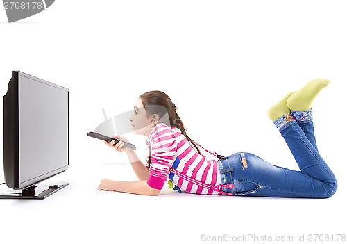 Image of Happy little girl with remote control watching tv