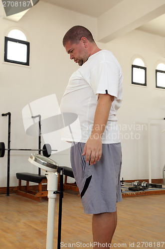 Image of man with overweight on scales in gym