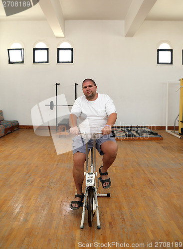 Image of overweight man on bike simulator