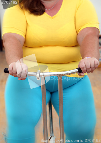 Image of overweight woman exercising on bike simulator 