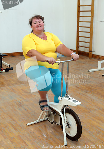 Image of overweight woman exercising on bike simulator