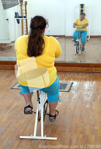 Image of overweight woman exercising on bike simulator
