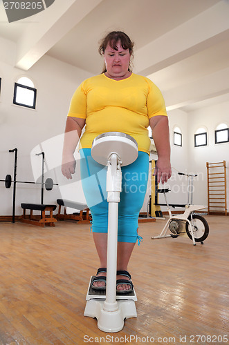 Image of women with overweight on scales in gym