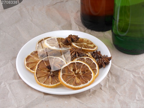 Image of beer bottle with cinnamon and lemon on white plate