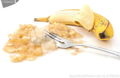 Image of Closeup of half-peeled banana with a fork in mashed puree