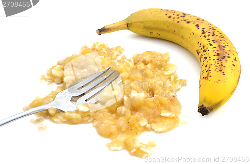 Image of Closeup of mashed banana with fork and an unpeeled fruit