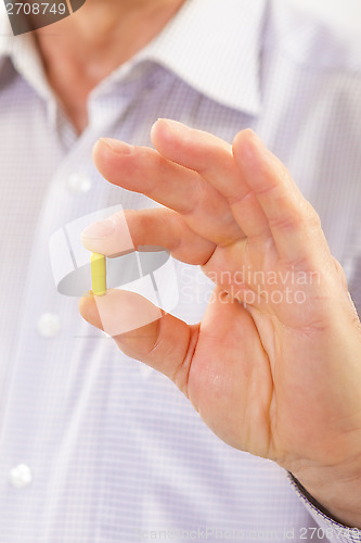 Image of Senior adult man holds medicine capsule 