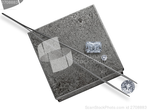 Image of diamonds and tweezers on a jeweler anvil