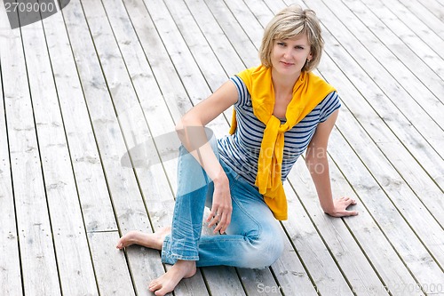 Image of Woman sitting on the weathered wooden floor