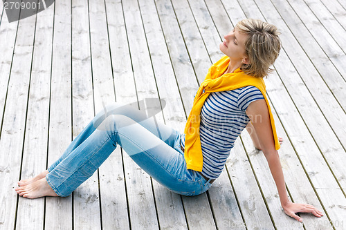 Image of Woman sitting with closed eyes on wooden floor