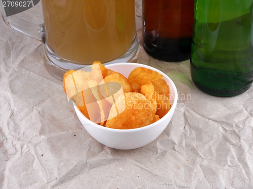 Image of Beer bottle and potato chips on white plate