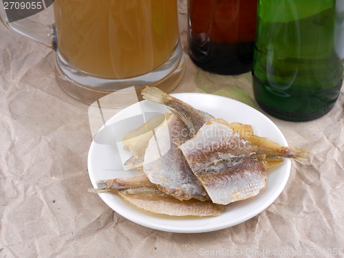 Image of fish on white plate and beer bottle