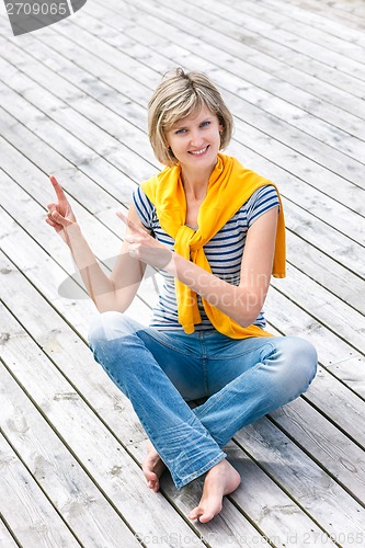 Image of Woman sitting on the weathered wooden floor