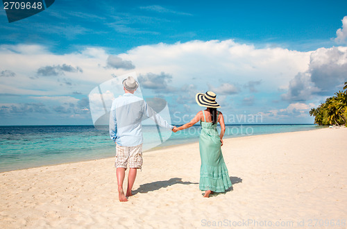 Image of Vacation Couple walking on tropical beach Maldives.