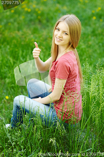 Image of Smiling female sitting outdoors gesturing thumb up