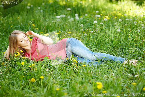 Image of Spring girl lying on the field of dandelions