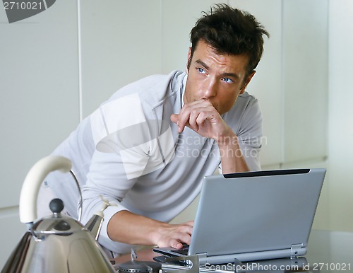 Image of man with computer in kitchen