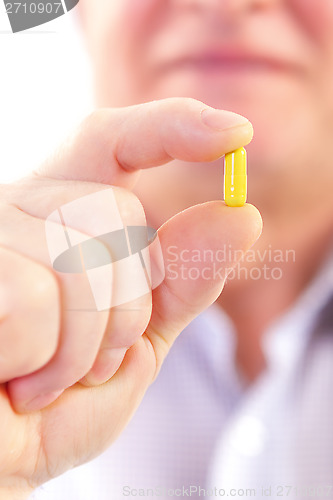 Image of Senior adult man holds medicine capsule