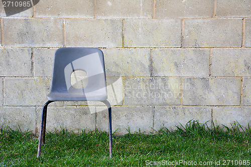 Image of Abandoned chair in front of a concrete block wall