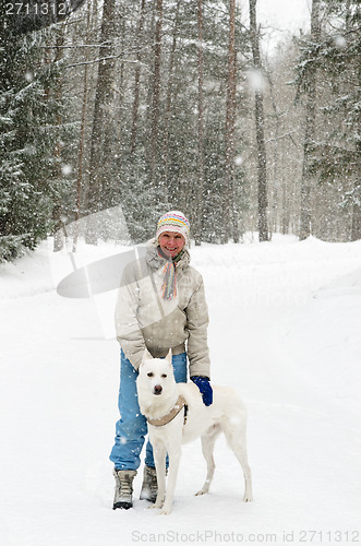 Image of Woman with a dog on a walk in the woods during a snowfall
