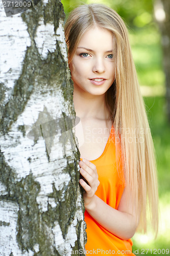Image of Beautiful female peeping from behind tree