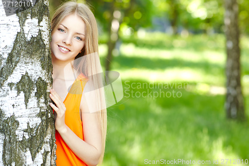 Image of Beautiful female peeping from behind tree