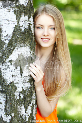Image of Beautiful female peeping from behind tree