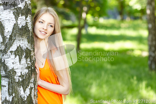 Image of Beautiful female peeping from behind tree